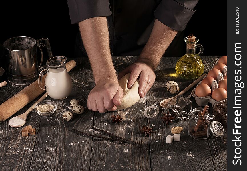 On table food and cooking utensils, dough in hands of Baker, isolated on black