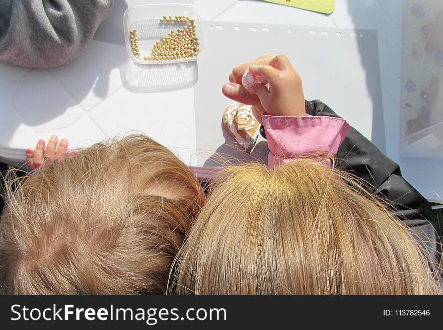 A child with his mother decorate with glaze and gold beads a small gingerbread. A child with his mother decorate with glaze and gold beads a small gingerbread