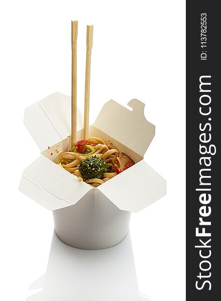 Spicy noodles with meat and vegetables in wok box, chopsticks isolated on white