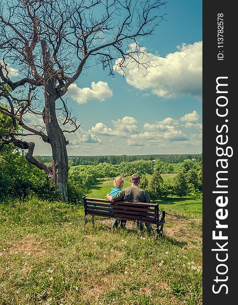 Elderly Husband And Wife Are Sitting On A Bench