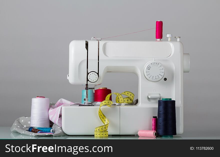 Household electric sewing machine and sewing supplies, on grey background