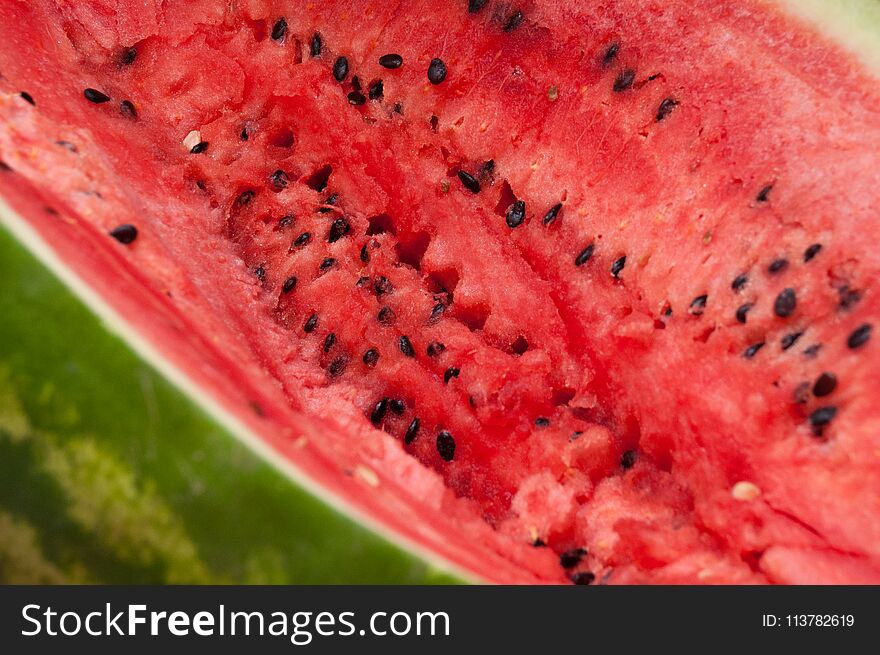 Red center of fresh watermelon with green striped peel and closeup of seeds. Red center of fresh watermelon with green striped peel and closeup of seeds