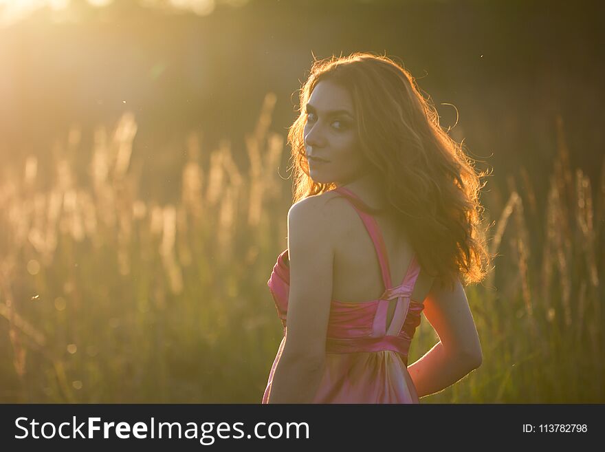 Portrait Of A Beautiful Young Woman In Meadow At Sunset