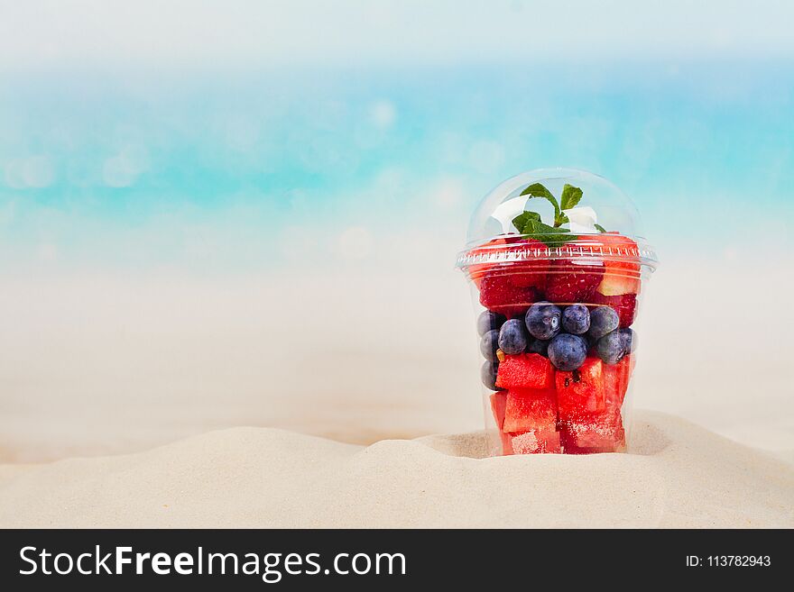 Plastic cup full of fresh cut fruits and berries