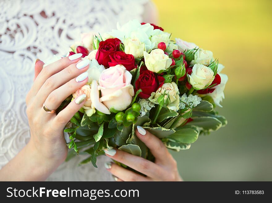 In the female hands a bouquet of the bride of red and white roses. In the female hands a bouquet of the bride of red and white roses