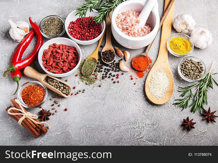 Different kind of spices in bowls on gray stone background