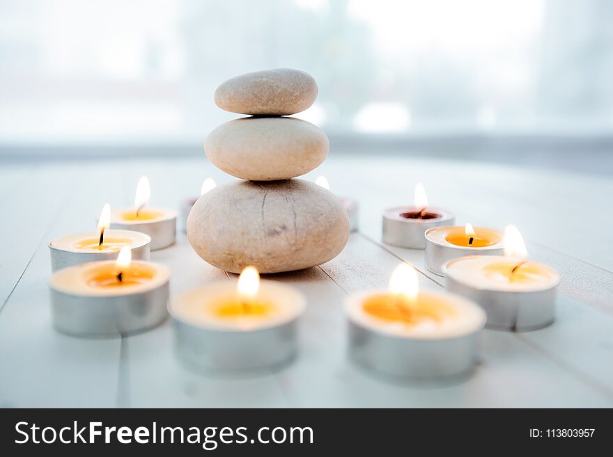 Zen Meditation Harmony, Spa Lifestyle, balanced stack of stones with aromatic candles on wooden white background. Zen Meditation Harmony, Spa Lifestyle, balanced stack of stones with aromatic candles on wooden white background