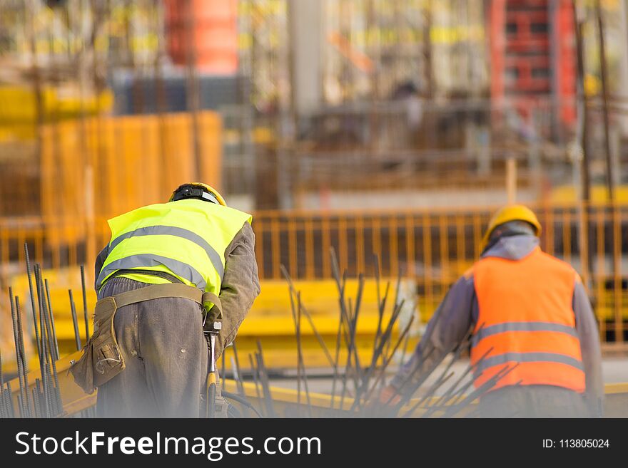 Two Builders In Yellow And Orange At The Construction Site