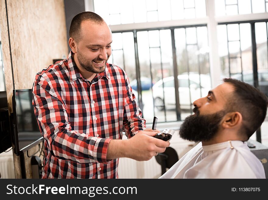 Barber cutting a beard with scissors at barber shop