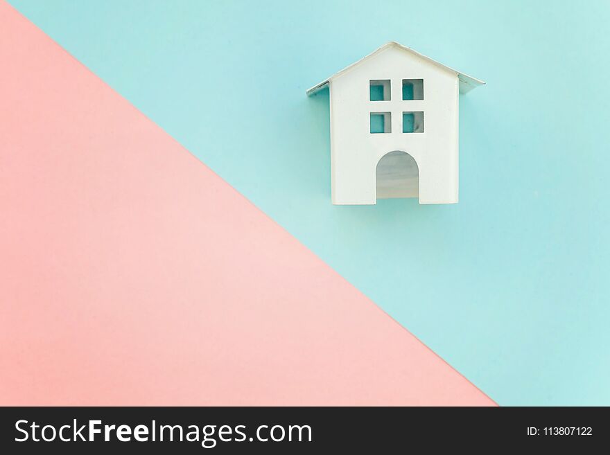Miniature white toy house on pink and blue pastel color paper geometric flat lay background. Mortgage property insurance dream home concept. Miniature white toy house on pink and blue pastel color paper geometric flat lay background. Mortgage property insurance dream home concept