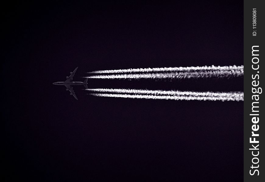 Photo of Airplane Across the Clouds during Night Time