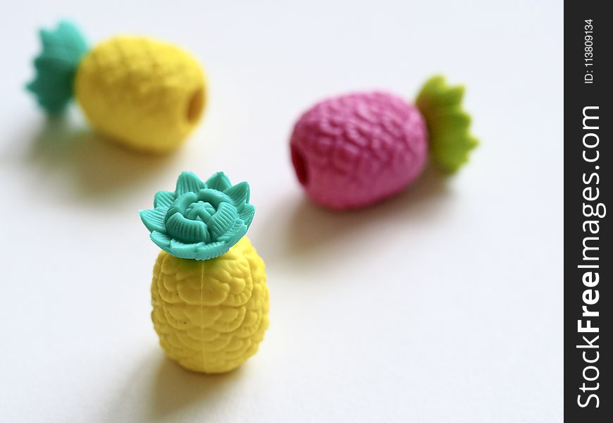 Three Plastic Pineapple Figures on White Surface