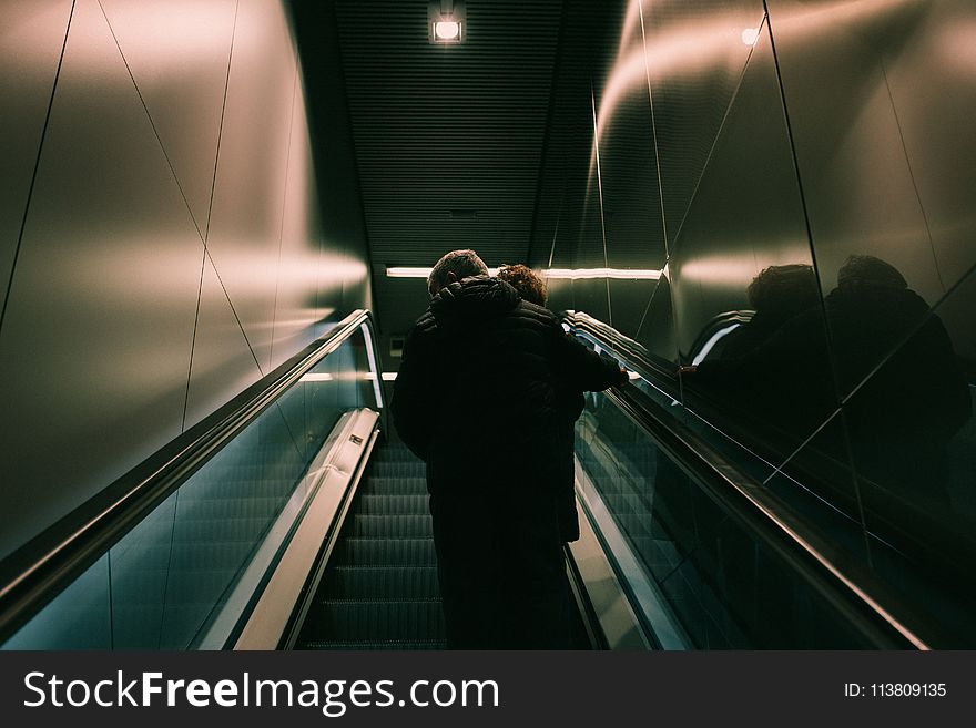 Person in Black Jacket Standing on Escalator