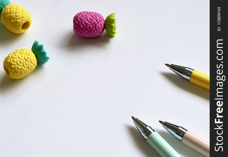 Closeup Photo of Three Assorted-color Pens Near Pineapples Miniatures
