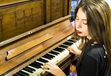A Young Woman Playing An Old Vintage Piano With Closed Eyes. Royalty Free Stock Images