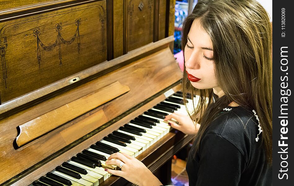 A young woman playing an old vintage piano with closed eyes.