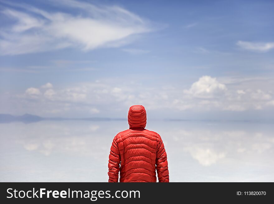 Young man in winter hooded jacket at Salar de uyuni salt flat in Bolivia