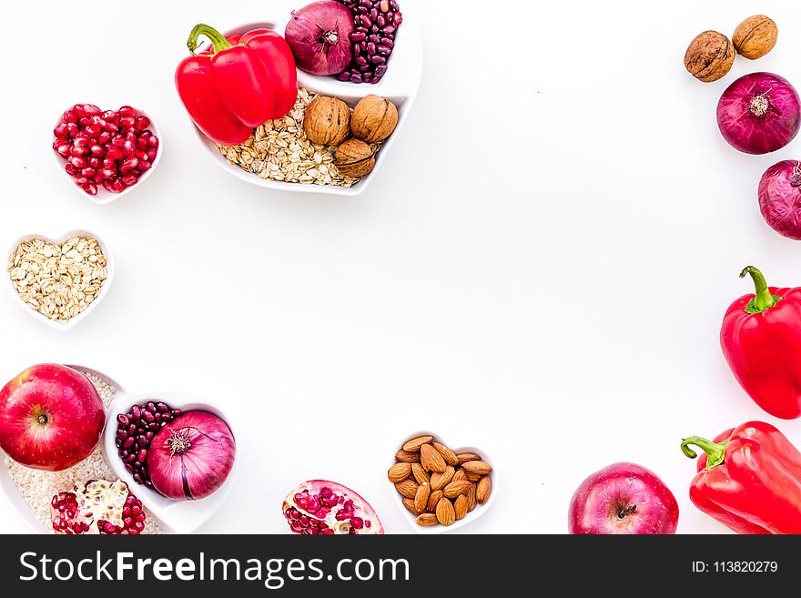 Diet for healthy heart. Food with antioxidants. Vegetables, fruits, nuts in heart shaped bowl on white background top view.