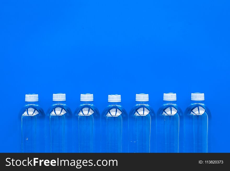 Drinking water in bottles on blue background top view copy space