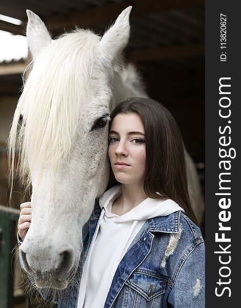 Portrait of a teenage girl touching a horse.