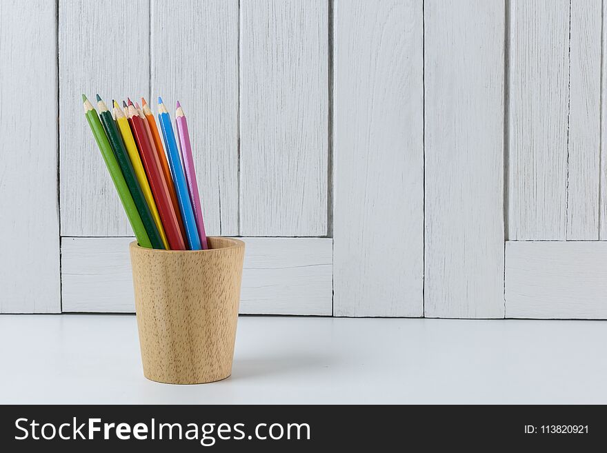 Education workspace background concepts Color Pencil in wooden cup with White wooden vintage wall. back to school concepts