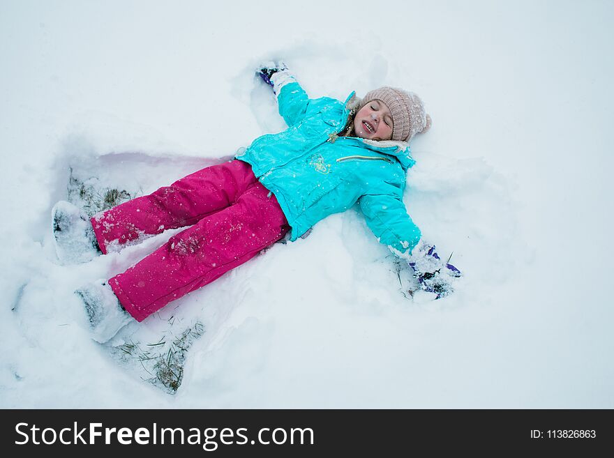 A young girl making snow angels in the driveway during in a winter storm