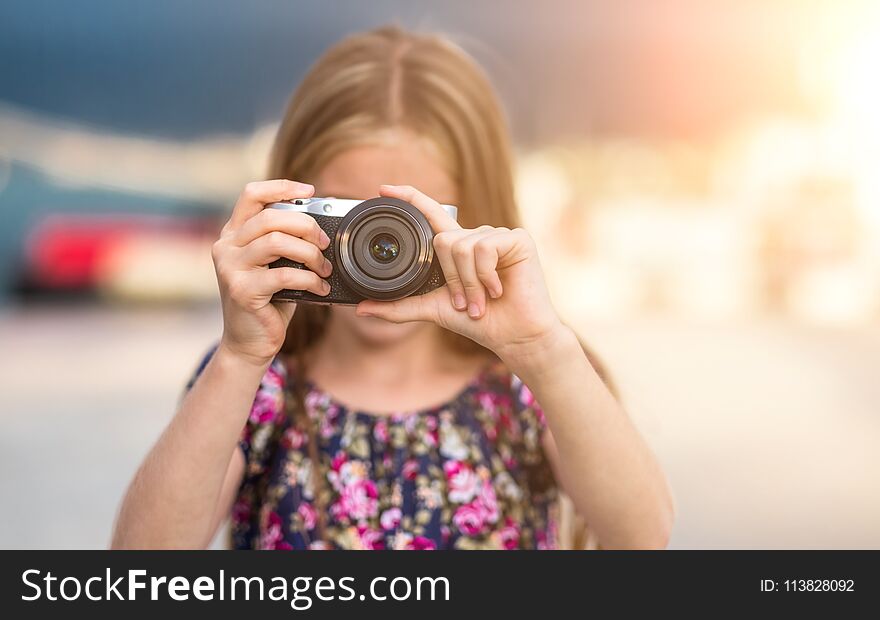 Beautiful little girl with camera takes a picture, summer outdoor