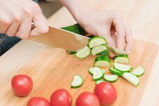 Close-up Of Female Hands Cut Into Fresh Cut Cucumbers On A Wooden Cutting Board Next To Pink Tomatoes. The Concept Of Stock Photos