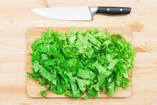 Close-up On A Wooden Table Is A Wooden Cutting Board On Which Lies Chopped Lettuce Leaves And Next To A Large Cutting Royalty Free Stock Images