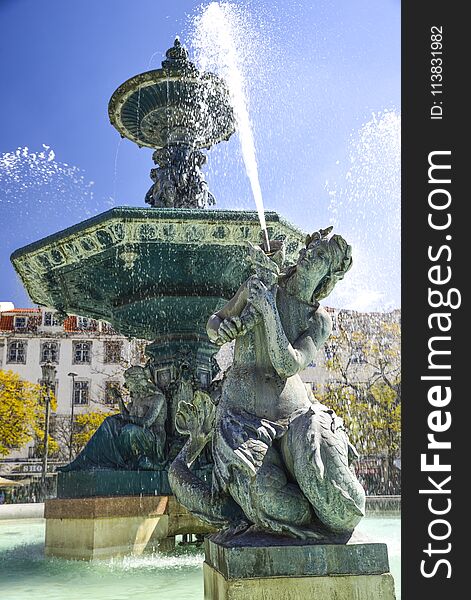 Bronze fountain in baroque style in piazza rossio Lisbon. woman statue in the foreground. Bronze fountain in baroque style in piazza rossio Lisbon. woman statue in the foreground