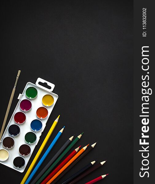 On dark background paint sheet brush pencils colored vertical top view flat lay background knolling