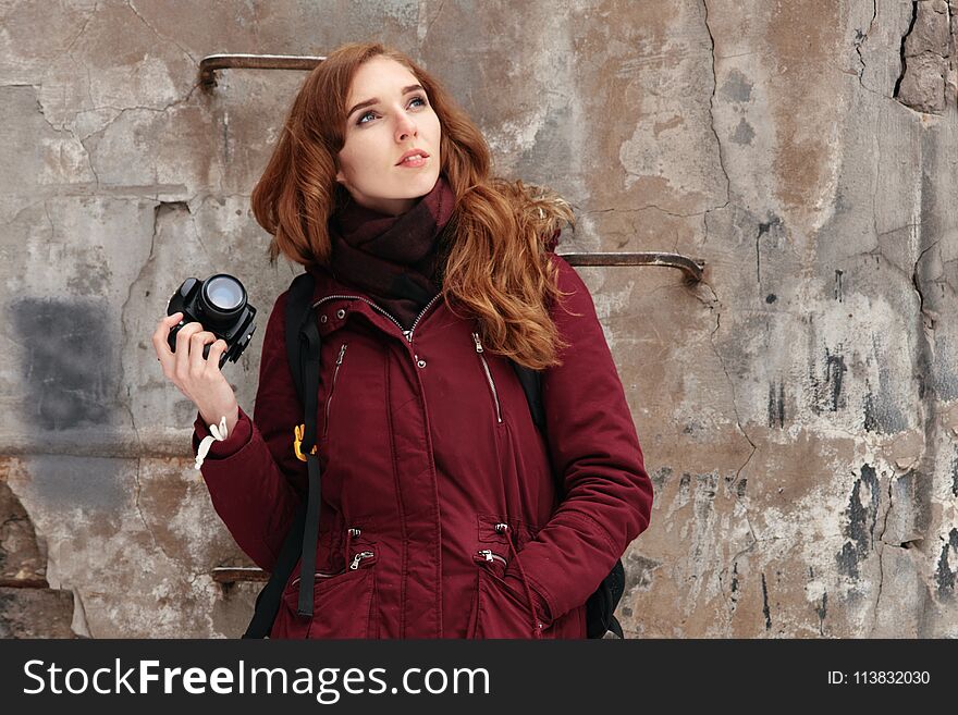 Young red-haired woman with photo camera on outdoor photo session