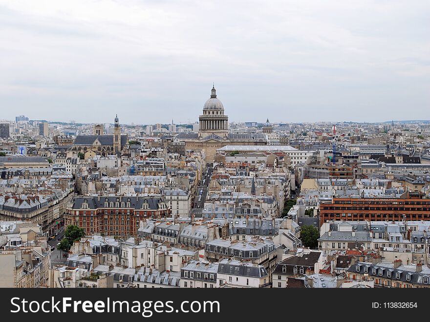 View of the dome of the Pantheon, towering over the roofs of Paris, against the background of a cloudy sky, from the height of the Notre Dame Cathedral. View of the dome of the Pantheon, towering over the roofs of Paris, against the background of a cloudy sky, from the height of the Notre Dame Cathedral.