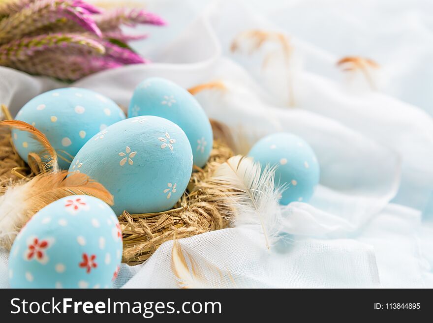 Happy easter! Colorful of Easter eggs in nest with flower, paper star and Feather on white cheesecloth background.