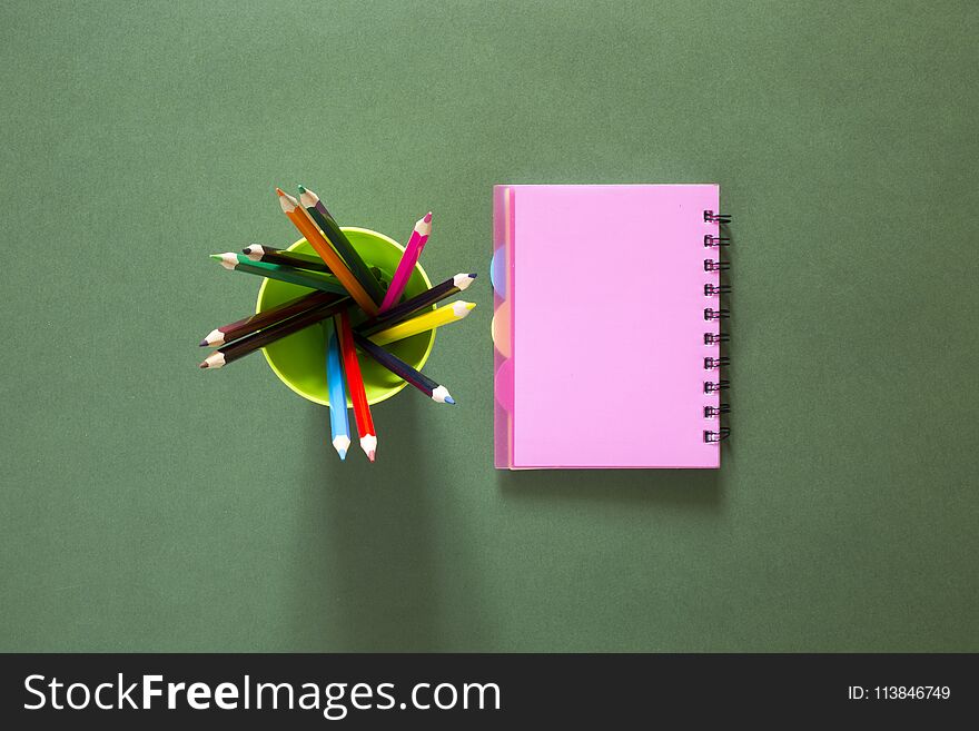 Set of colored pencils and a pink notebook