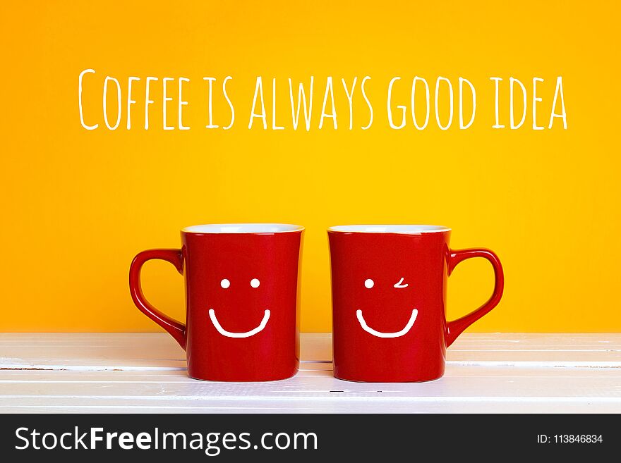 Two red coffee mugs with a smiling faces on a yellow background with the phrase Coffee is alwayas good idea. Happy coffee mugs.