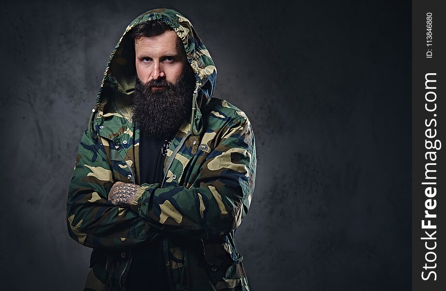 Urban Look Bearded Male With Crossed Arms Dressed In A Camouflage Jacket.