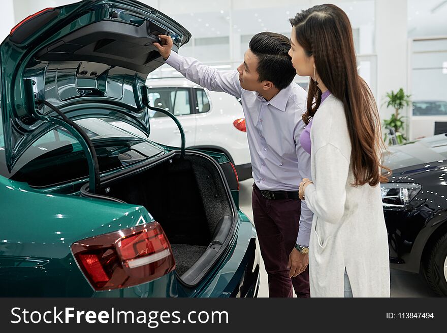 Vietnamese married couple checking trunk closing mechanism. Vietnamese married couple checking trunk closing mechanism