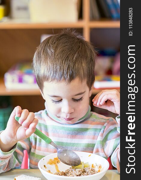 A Boy At The Age Of 5 Years Eating Gruel In The Kindergarten.