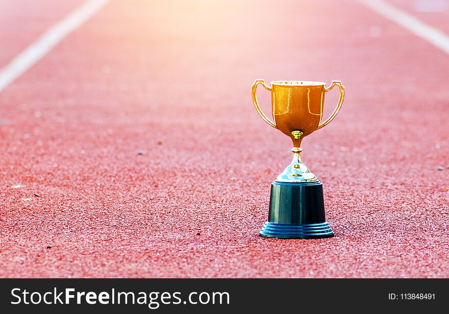 Gold trophy on red Track in stadium ,leadership ;success in business concept