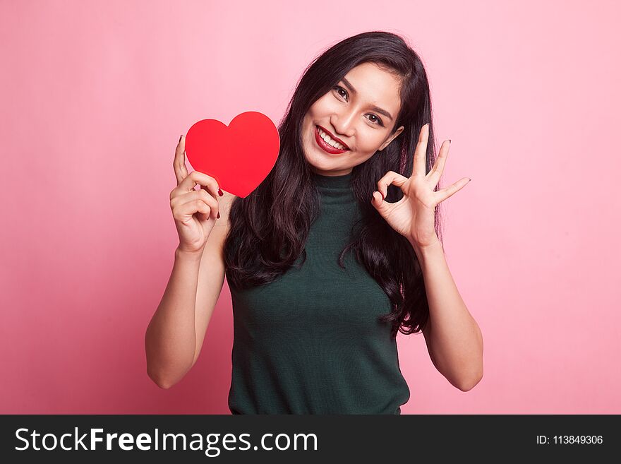 Asian woman show OK with red heart on pink background. Asian woman show OK with red heart on pink background