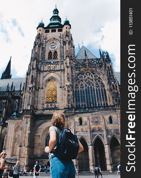 Woman Wearing Backpack And Grey Shirt Near Brown Church