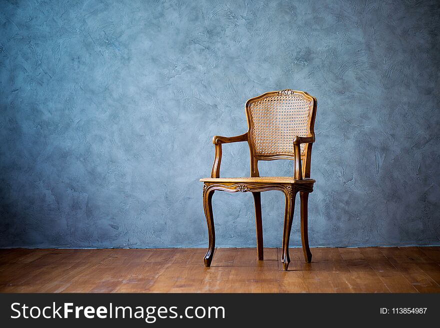 Old chair on a gray wall background.