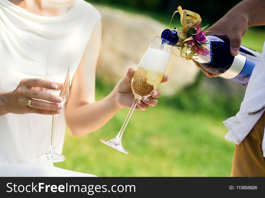 Man pours champagne into glasses which holds woman. Man pours champagne into glasses which holds woman