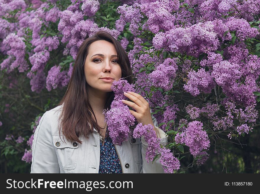 Beautiful woman and blooming lilac in the garden