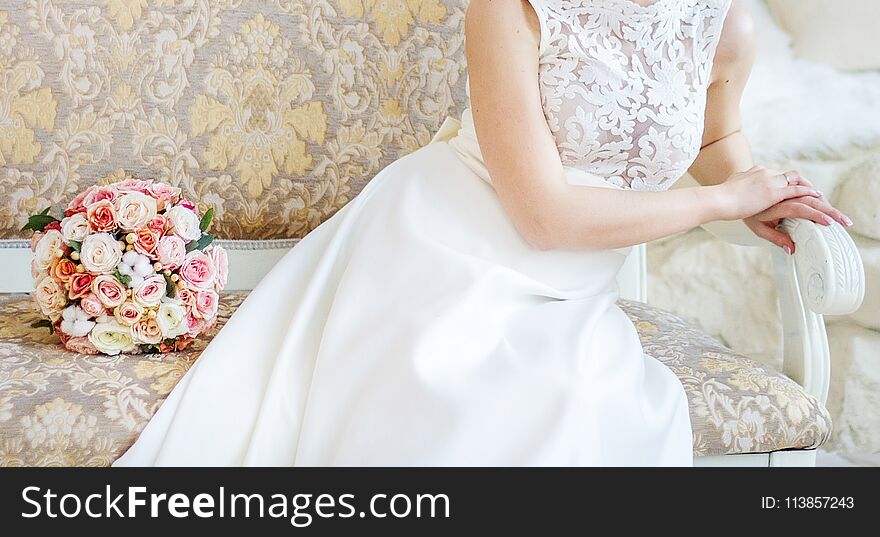 Bridal bouquet lies on a bench near a bride indoor closeup