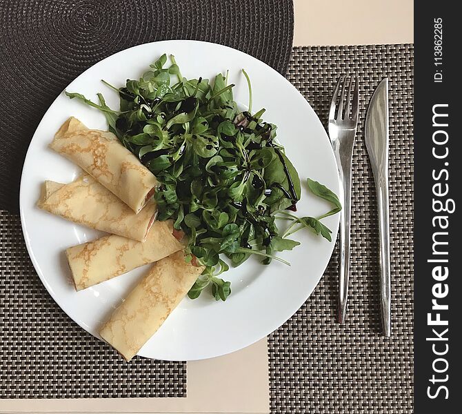 A bright snack of Russian bliny or crepes and arugula with balsam. A bright snack of Russian bliny or crepes and arugula with balsam