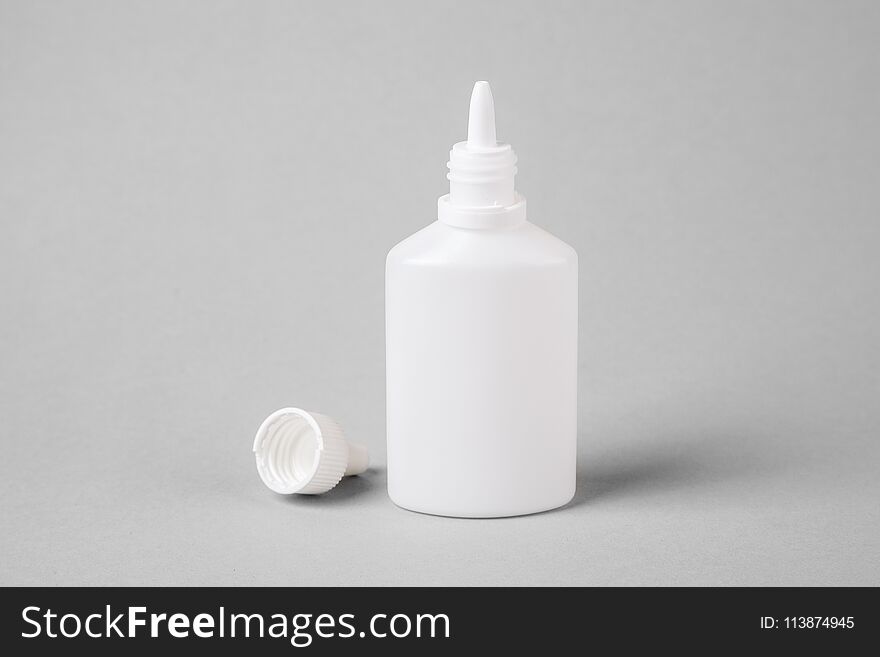 Spray for the nose in a white plastic bottle on a gray background. Aerosol from the common cold or allergy