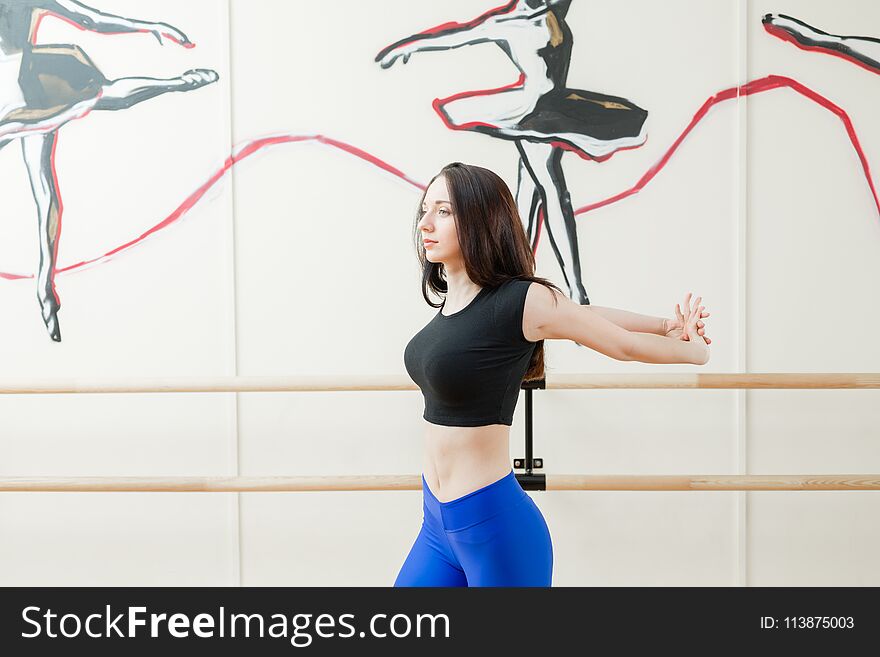 Cute young girl wearing black top and blue pants doing physical exercises warming up. Physical activity concept