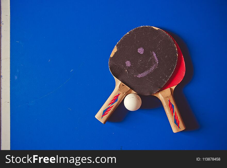 Two fryed tennis rackets on a blue tennis table background.